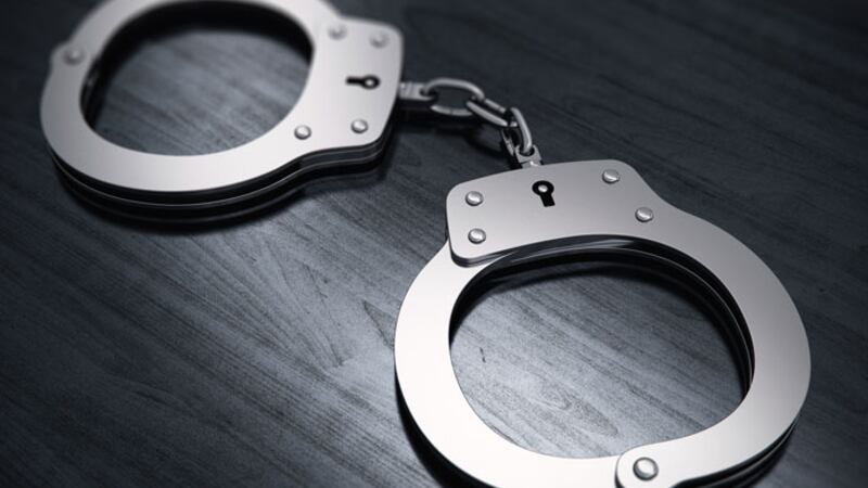 A pair of handcuffs lays on black wood. (Source: Raycom Media)